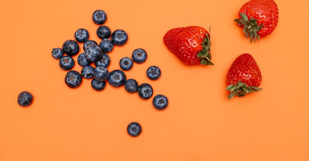 A vibrant still life of fresh blueberries and strawberries on an orange backdrop.