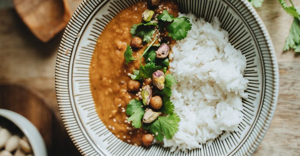 Delicious vegan rice bowl featuring lentil curry, topped with pistachios, cilantro, and sesame seeds.